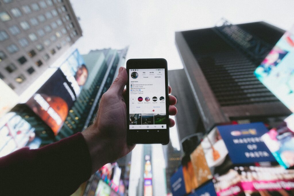 Hand holding a phone displaying social media and digital marketing content